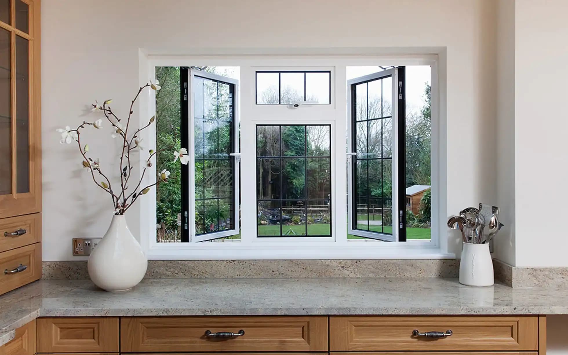 Bright contemporary kitchen featuring large energy-efficient aluminium windows providing panoramic garden views and abundant natural light